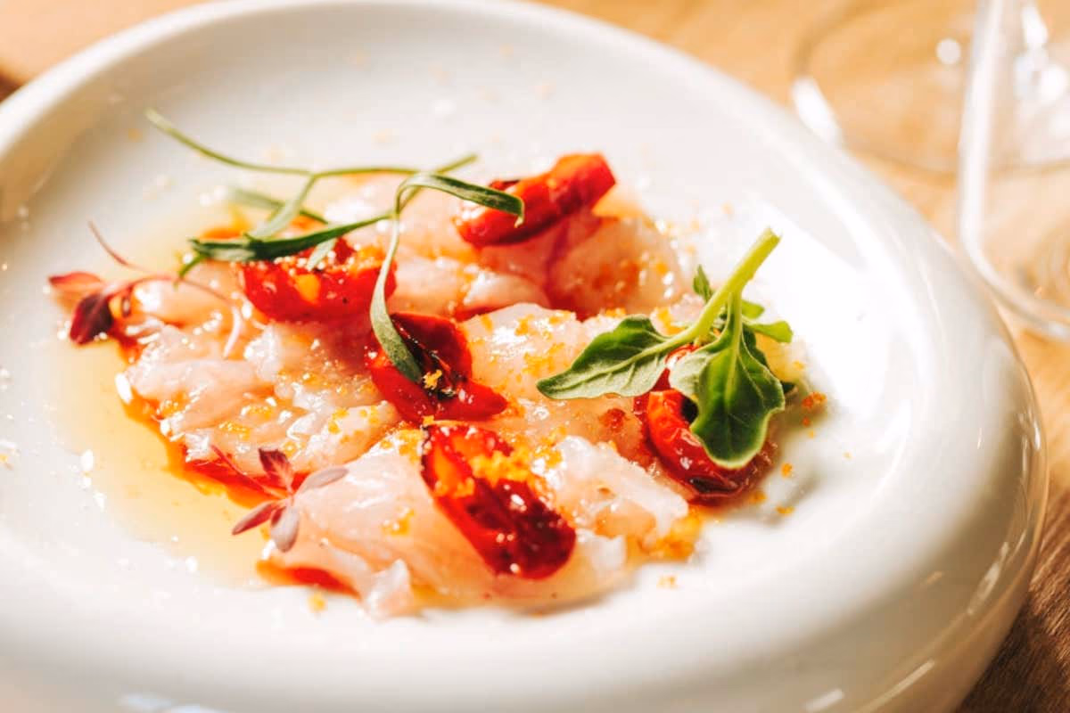 Carpaccio di pescato con olio al porro, riduzione di aceto, pomodoro bruciato e bottarga